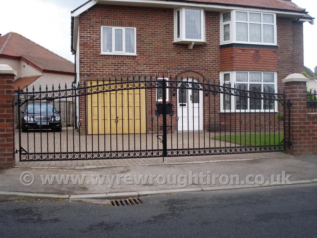 Wide span double arch driveway gates with railheads and scrolled tail circles, installed to a house in Cleveleys. Galvanised and powder coated in black